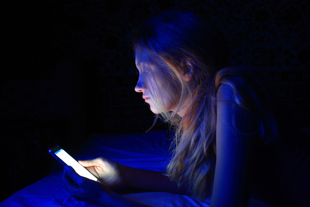 A woman on her phone at night, a common cheaters' practice.